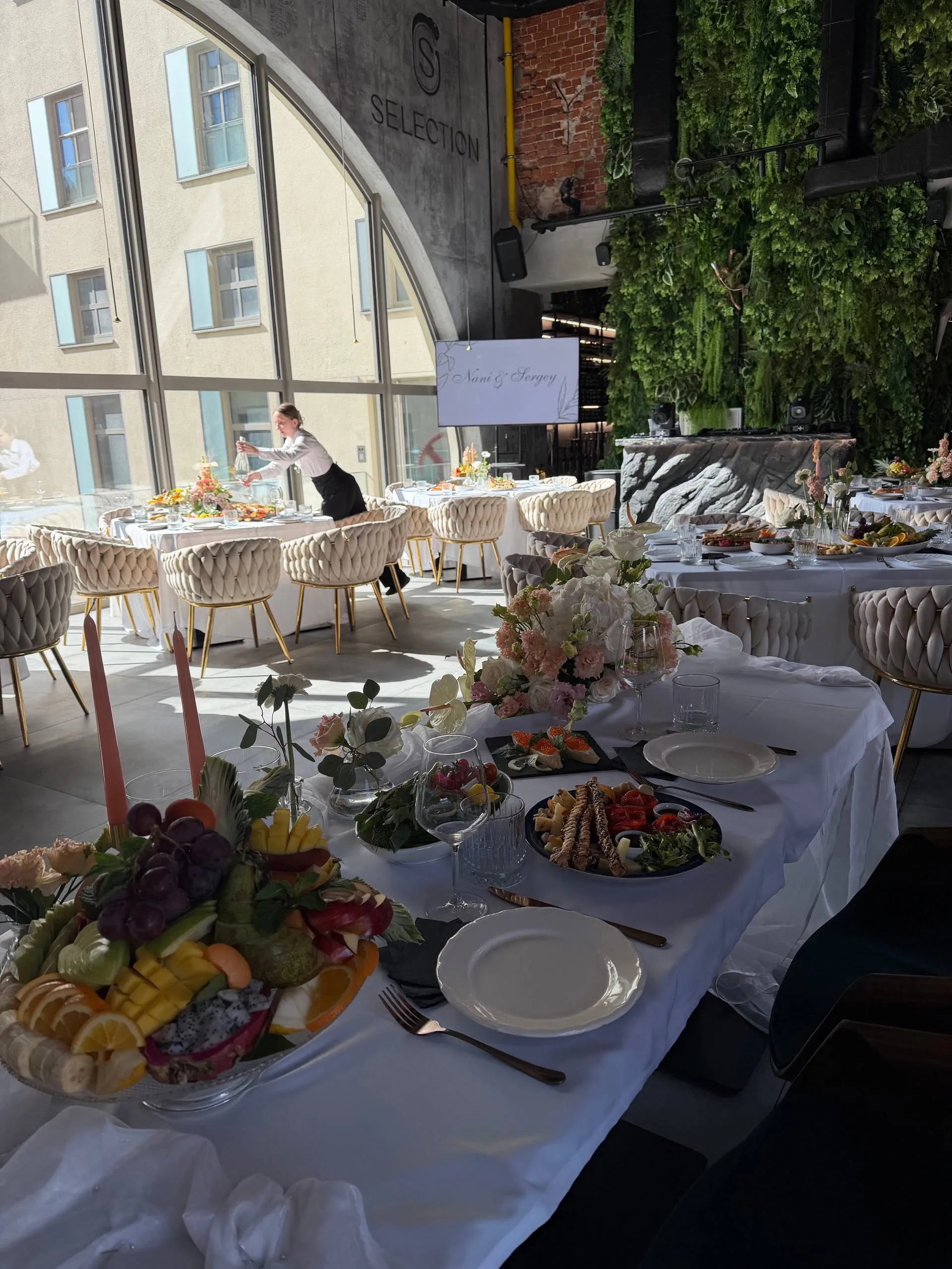Elegancko nakryty stół na przyjęcie firmowe w Selection — kwiaty, owoce i przekąski przy panoramicznym oknie